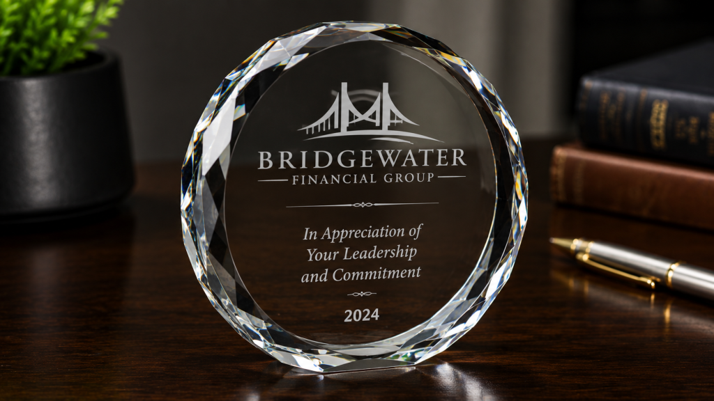 Round faceted crystal paperweight award engraved with a corporate logo and leadership appreciation text.