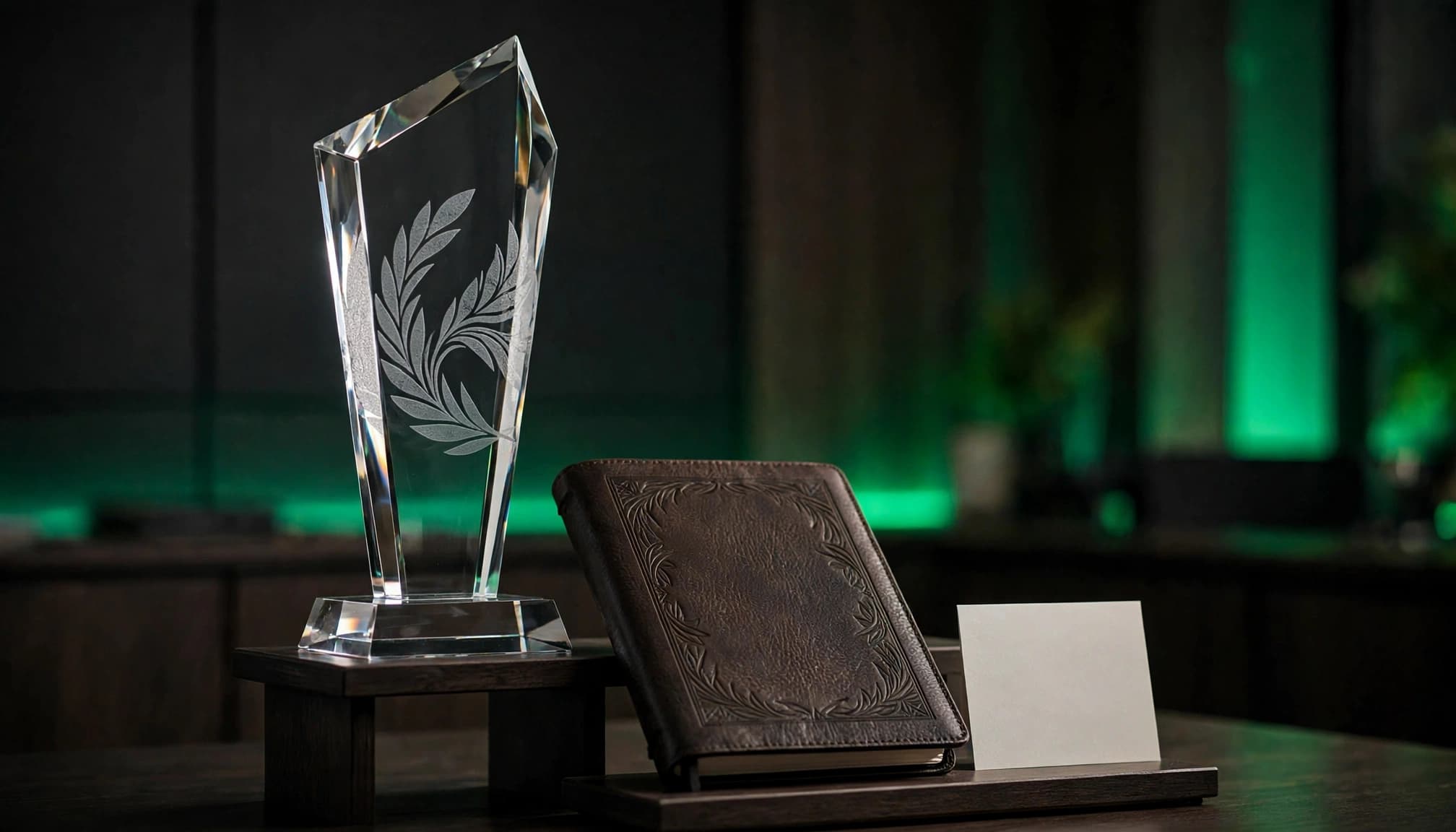 An engraved glass award and leather notebook displayed beside a blank card.